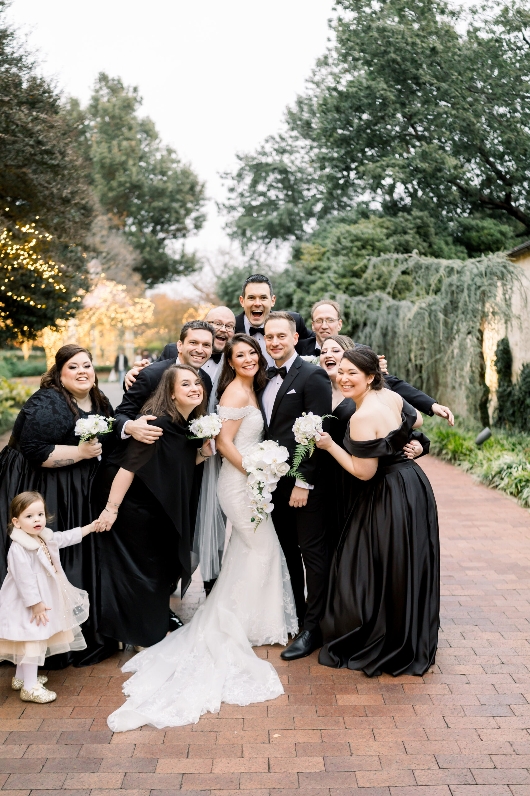 A bridal party in elegant dresses gathered in a light-filled, editorial setting.