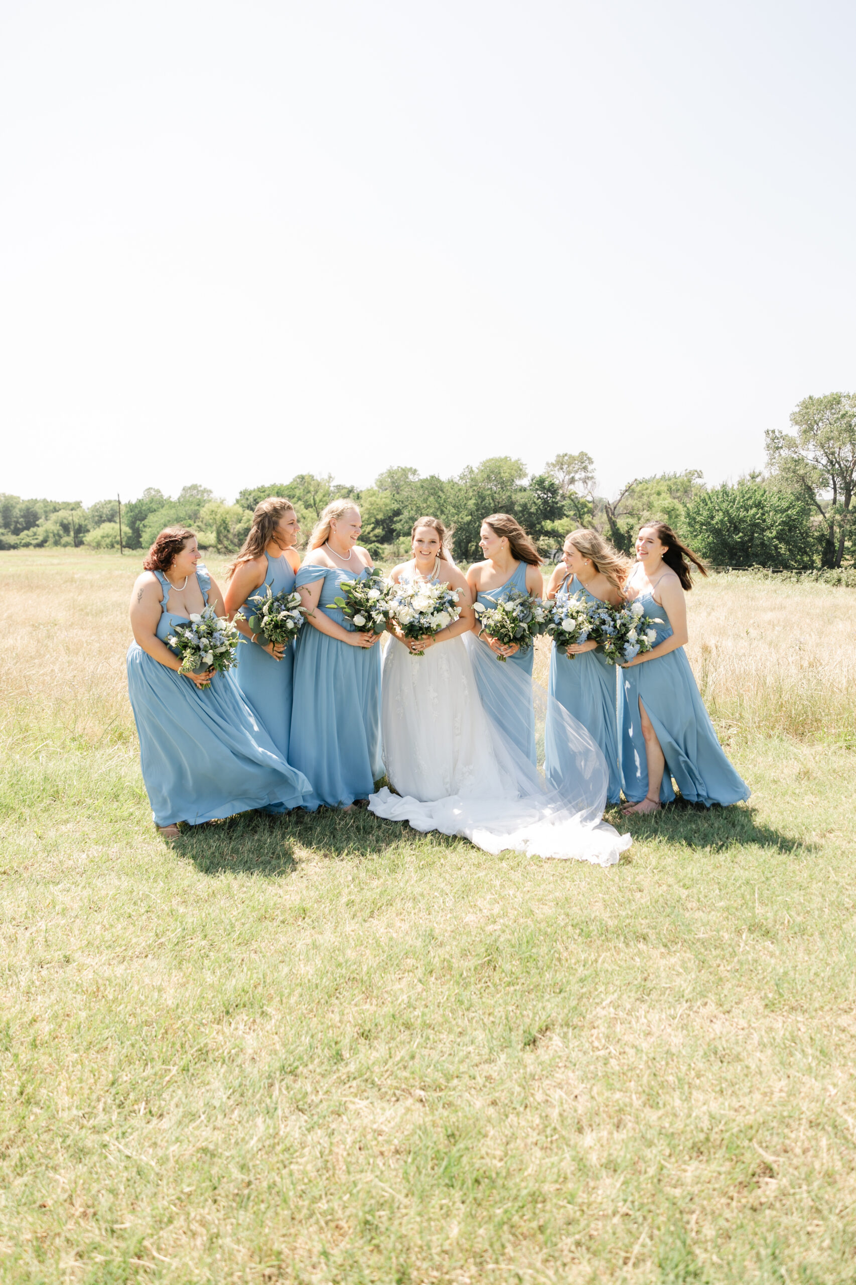 Bridesmaids in elegant dresses sharing a soft, celebratory moment before the wedding.