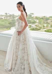 Saige wedding dress by Morilee featuring a sheer corset bodice, strapless sweetheart neckline, and floral burnout organza ball gown with detachable Watteau train