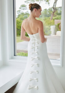 Susanna wedding dress by Morilee, style 2735, featuring a minimalist strapless satin bodice with princess seams and bow-accented train