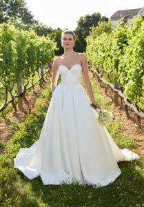 Sofina ball gown wedding dress by Morilee featuring a sweetheart corset bodice, draped bust, detachable off-the-shoulder sleeves, and pleated satin skirt with side bustles